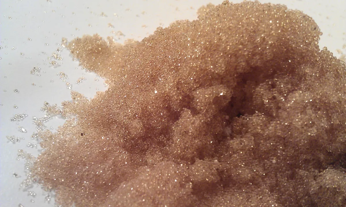 A small pile of tiny translucent amber resin beads on a white surface.