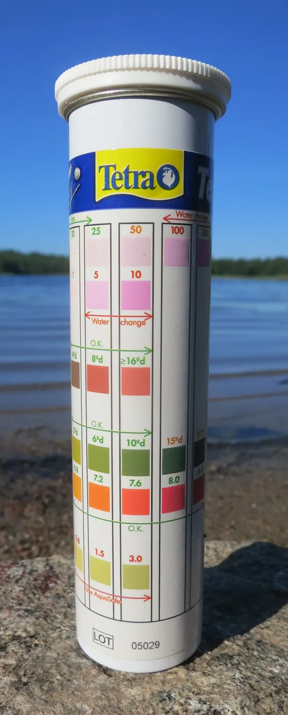 A cylindrical container of 6-in-1 water test strips with a printed color chart for nitrate, nitrite, general hardness, carbonate hardness, pH and chlorine.